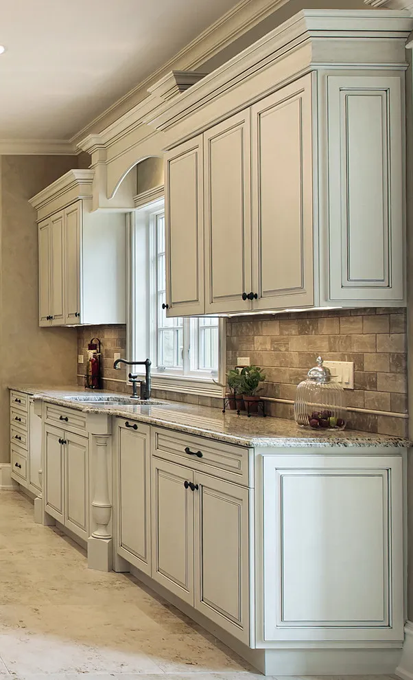 Warm white doors with raised panels and crown molding sit above a pale stone counter