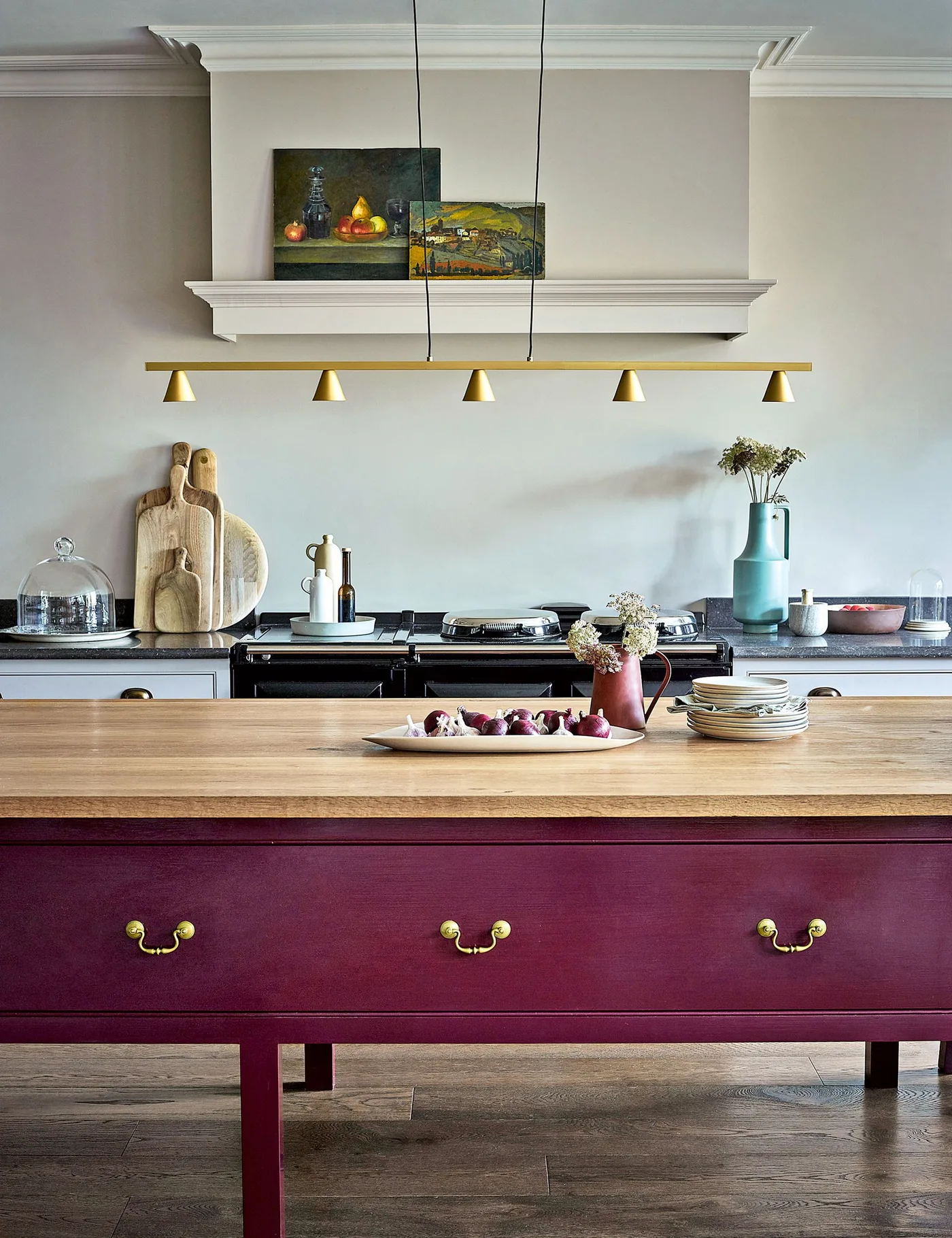 Kitchen with a plum-painted drawer island, wooden worktop, pale blue wall and range cooker beneath a broad pale hood.