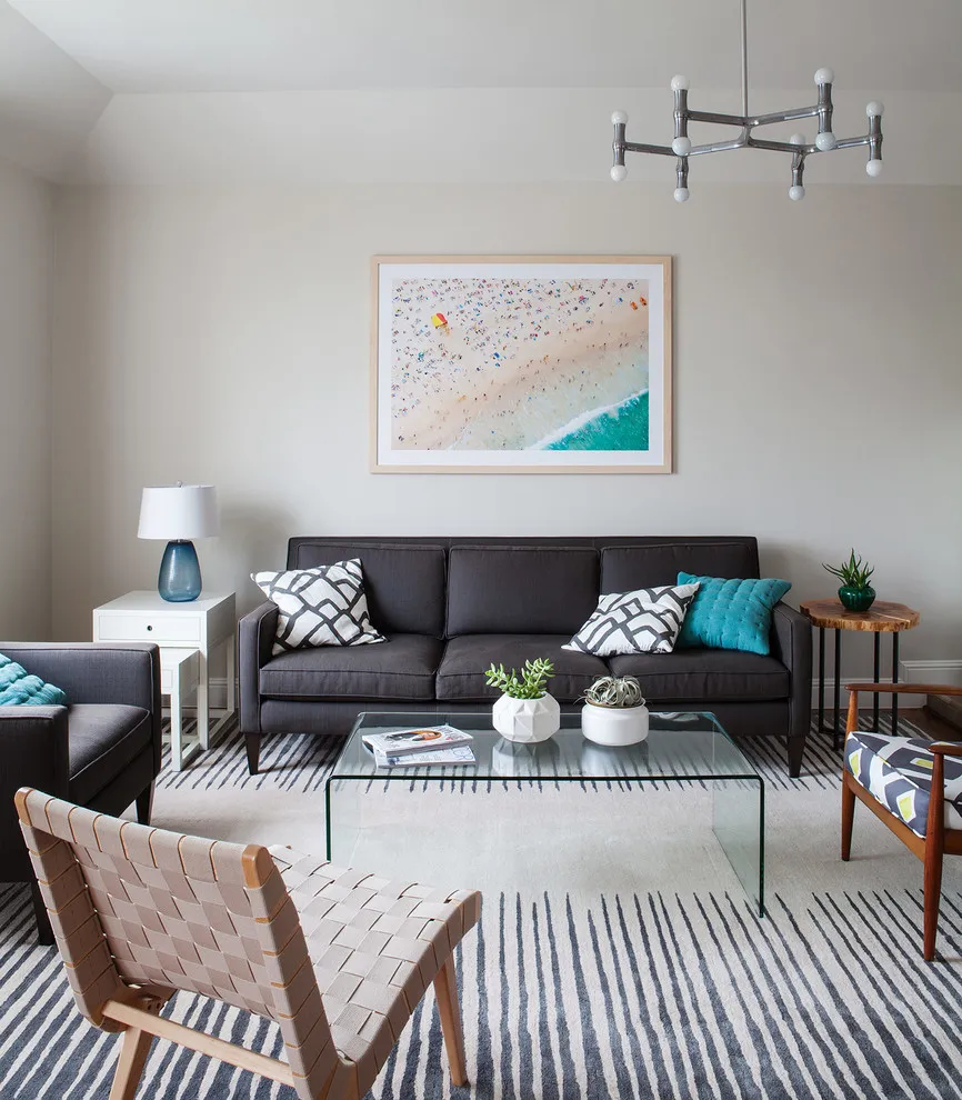 Beach photograph in a pale frame above a dark sofa with turquoise cushions