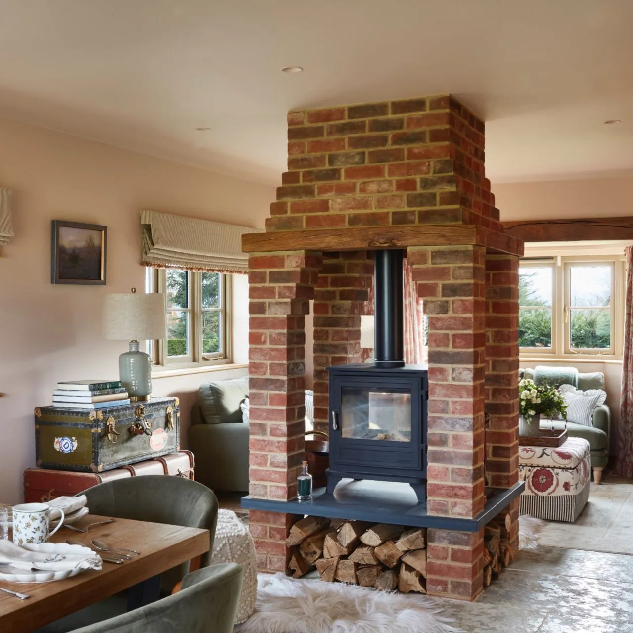 A substantial brick hearth stands between seating and dining furniture in a relaxed room.