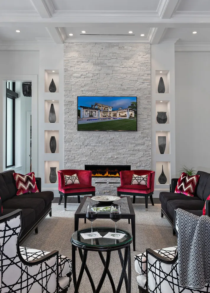 Red upholstered chairs sit against a bright fireplace wall beside dark seating