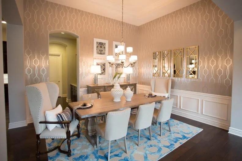 Pale blue dining chairs and tall end chairs around a wooden table beneath a chandelier against beige patterned wallpaper.