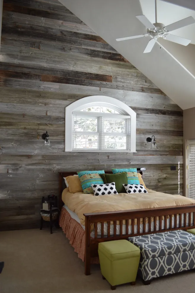 Weathered horizontal timber covers a sloped bedroom wall around an arched window