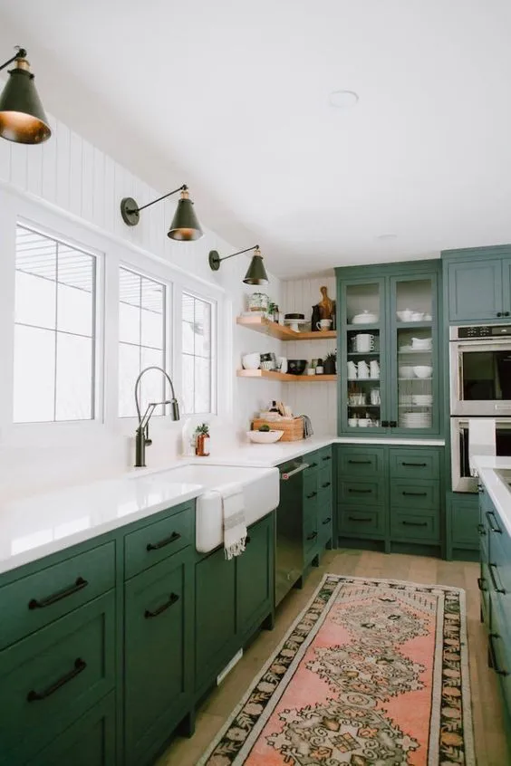 Green lower cabinets sit below white tile and a bright sink window