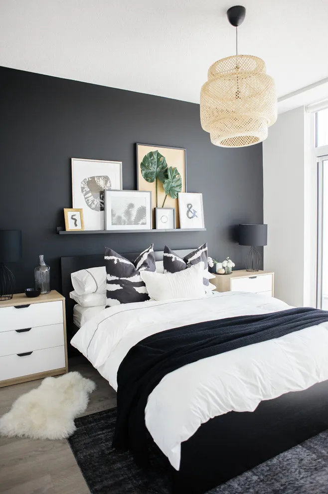 A dark wall frames pale bedding beside white side walls and a woven pendant