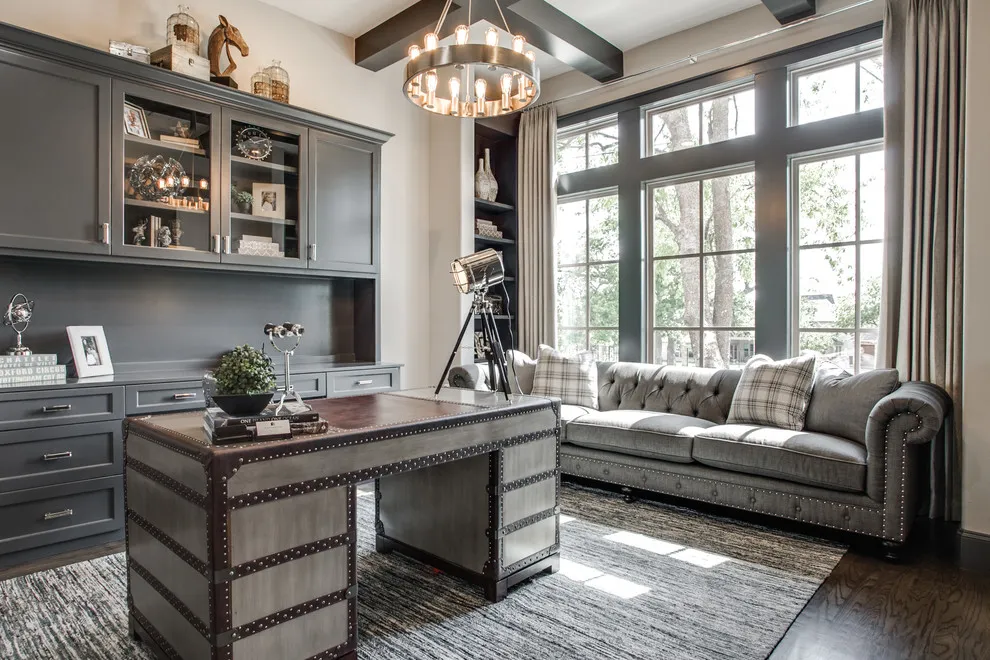 A tufted gray sofa sits beside dark built-in cabinetry and a desk in a bright living room
