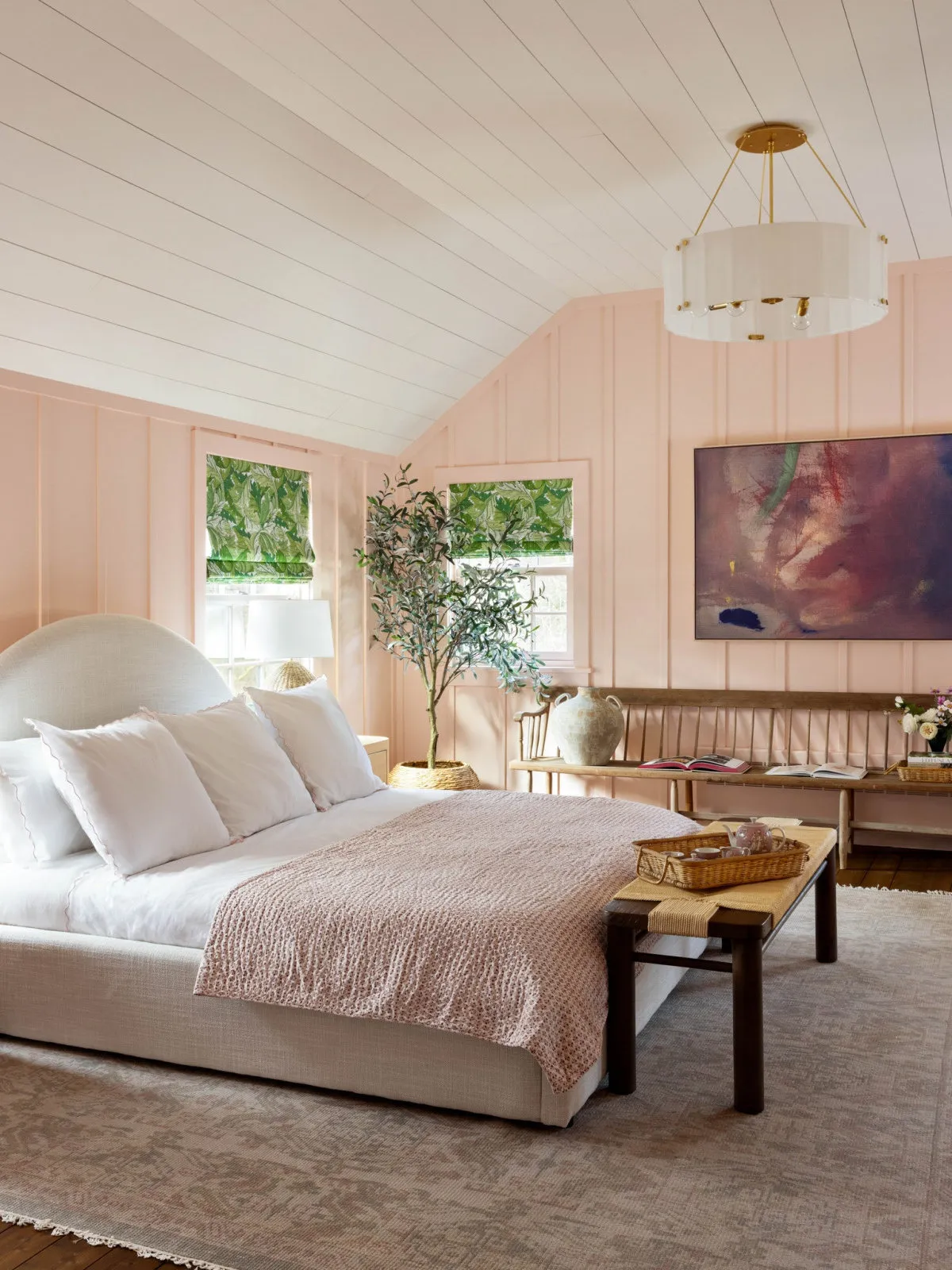 Pale pink walls surround light bedding, a timber bench and darker country furniture.