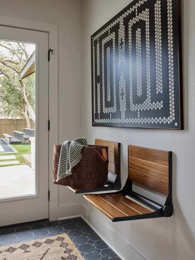 Entry with two wall-mounted folding wooden seats, large dark patterned artwork, glazed door and geometric mat.