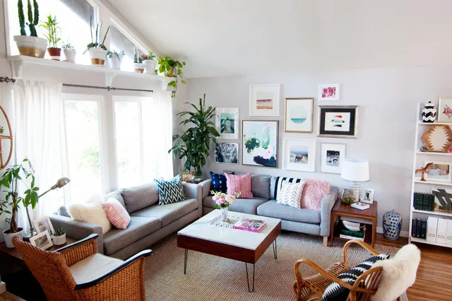 Small framed pictures hang above pale seating and varied timber tables in a bright room.