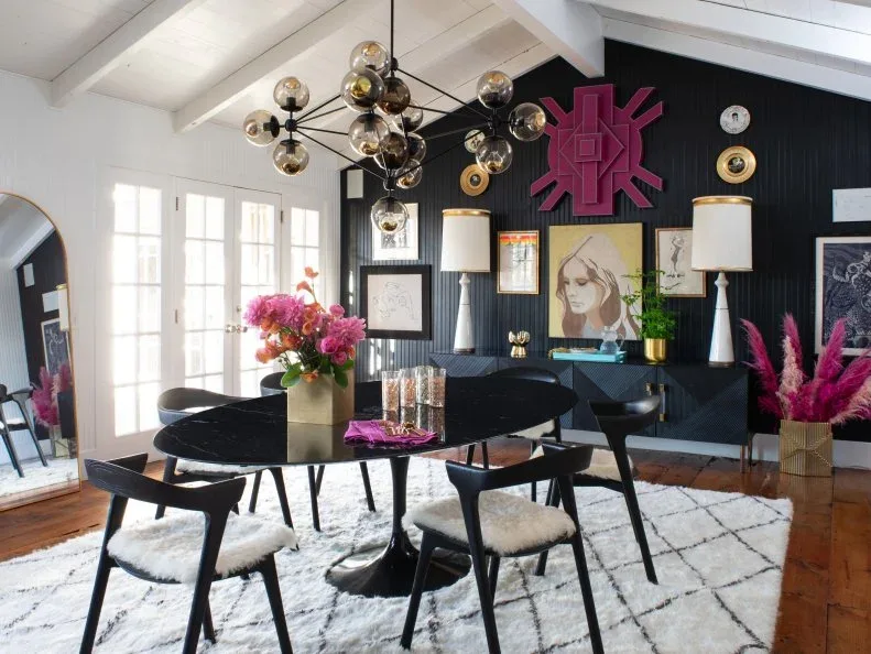 Black diamond-front sideboard beneath a dense gallery wall and two pale lamps behind a dark dining table