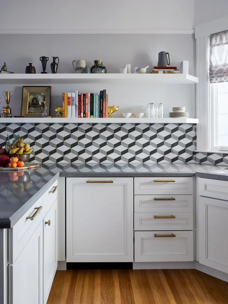 White kitchen with black-and-white geometric backsplash, open shelves, books and pale cabinets.