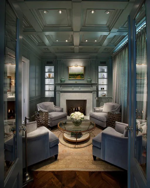Deep blue-green paneling surrounds a pale seating group and fireplace.