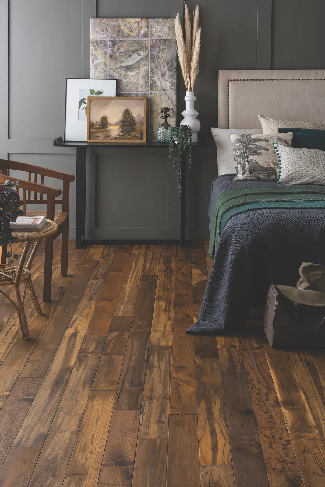 Dark wood boards with varied grain run beside a gray paneled bedroom wall