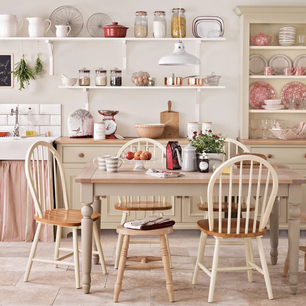 Cream-beige dresser displaying dishes beside a wood dining table and pale chairs