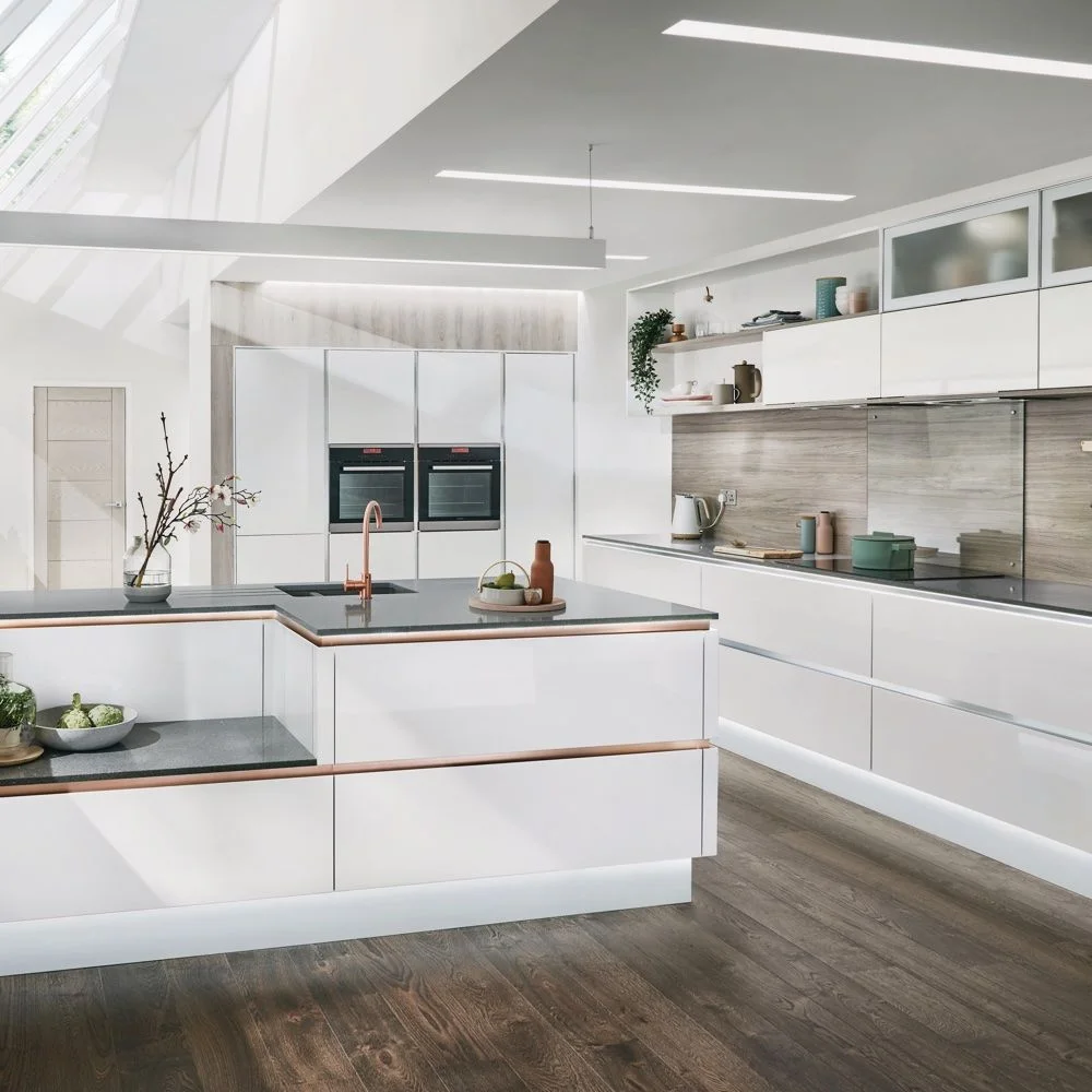 Pale kitchen drawers with narrow warm-colored edge details surround a smaller peninsula below a long wall cabinet, skylight and gray backsplash