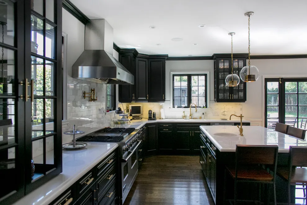 Dark cabinets line a bright kitchen beside tall black-framed windows and a pale counter