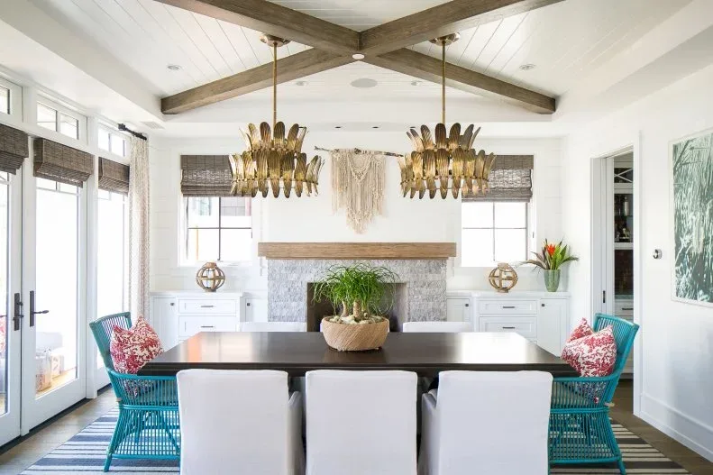 Two gold-toned sculptural lights above a long dark table with white side chairs and turquoise end chairs