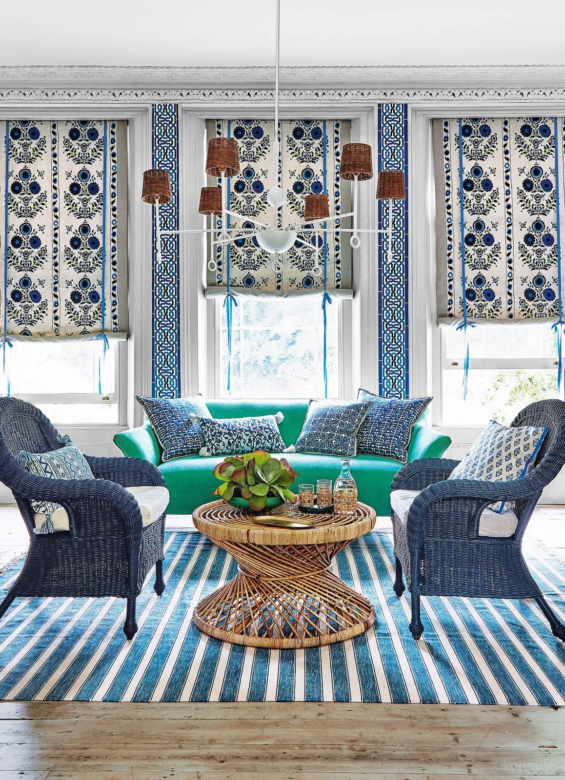 Blue woven chairs face a green sofa above a blue-and-white striped rug.
