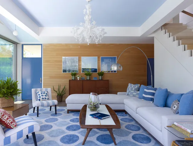 A pale blue ceiling section sits above light seating and a blue patterned rug.