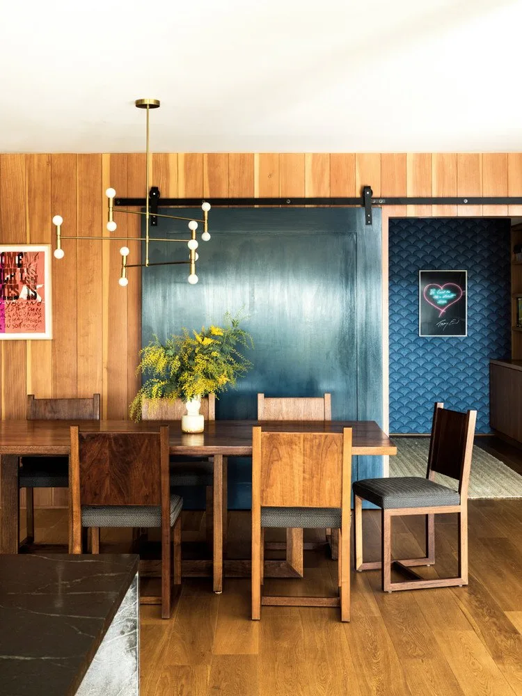 Wood dining wall panels beside a deep blue sliding door and patterned blue recess with framed pictures