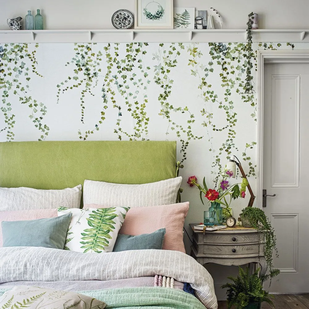 Green trailing-leaf wallpaper below a white display ledge behind a lime headboard and pale bedding.