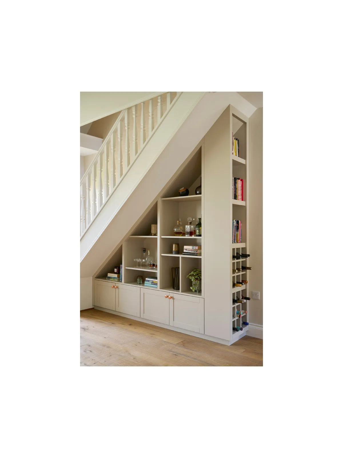 Pale storage fits beneath a staircase with open shelves beside lower cupboards.