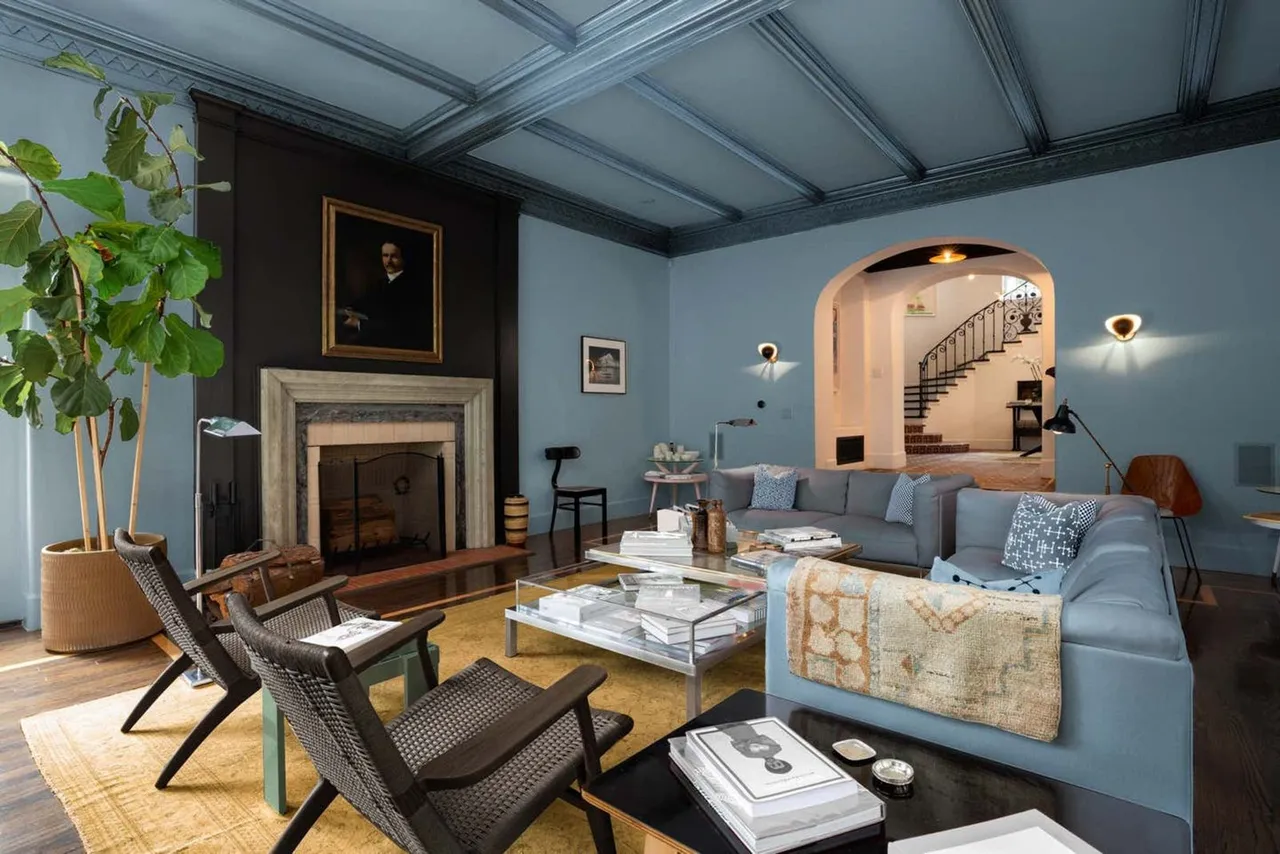 Soft blue walls and ceiling details surround pale seating and darker chairs.