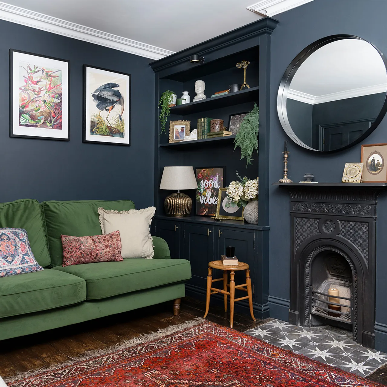 A green sofa sits beside dark built-in shelves and a patterned rug