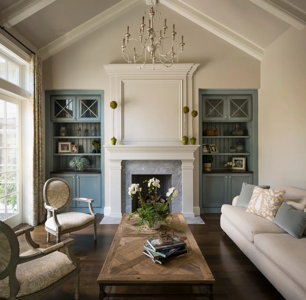 A round-backed chair sits beside a pale sofa and a long timber table near a fireplace