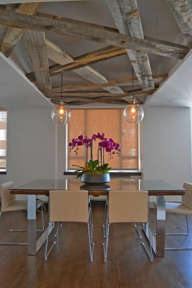 A simple table stands beneath exposed ceiling structure and glass pendant lights