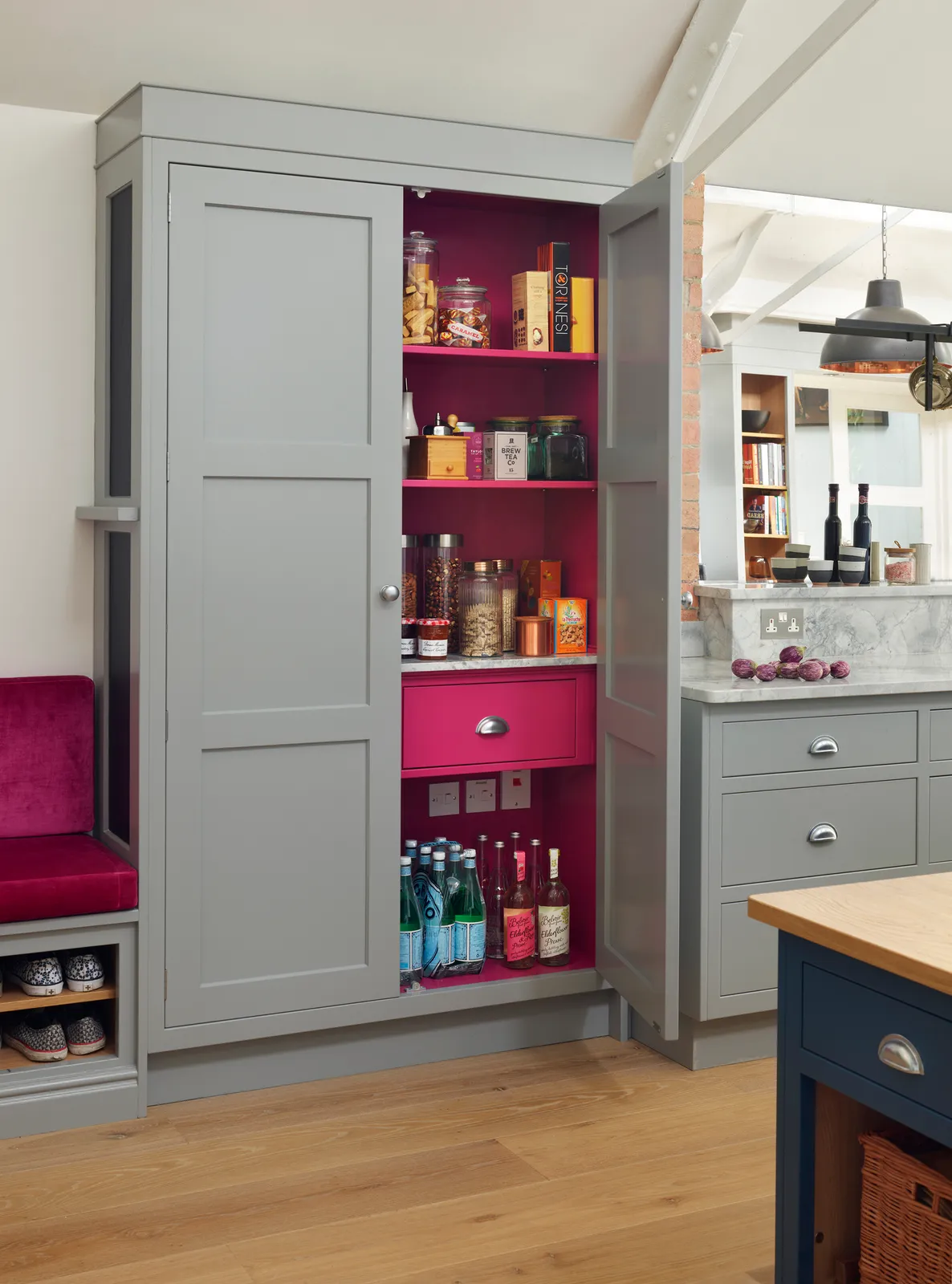 A gray pantry opens to reveal bright pink shelves and drawers