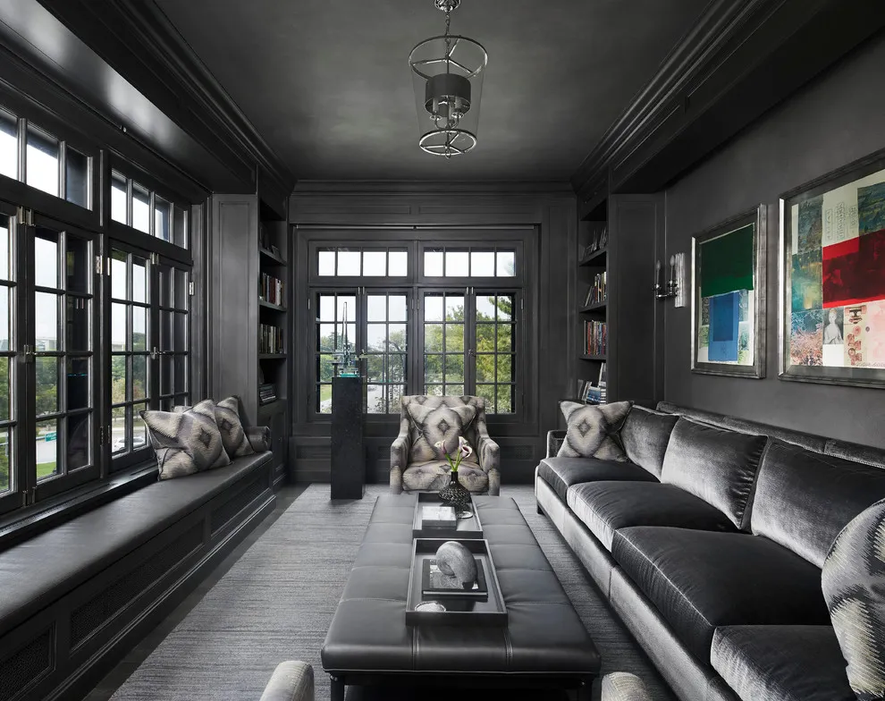Gray sofas and a cushioned window seat occupy a room with dark walls and black window frames