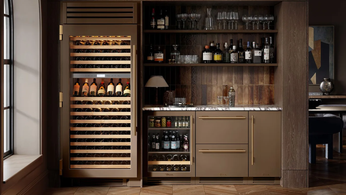 Brown drinks cabinet with a tall wine refrigerator, bottle shelves, glassware and warm metal handles.