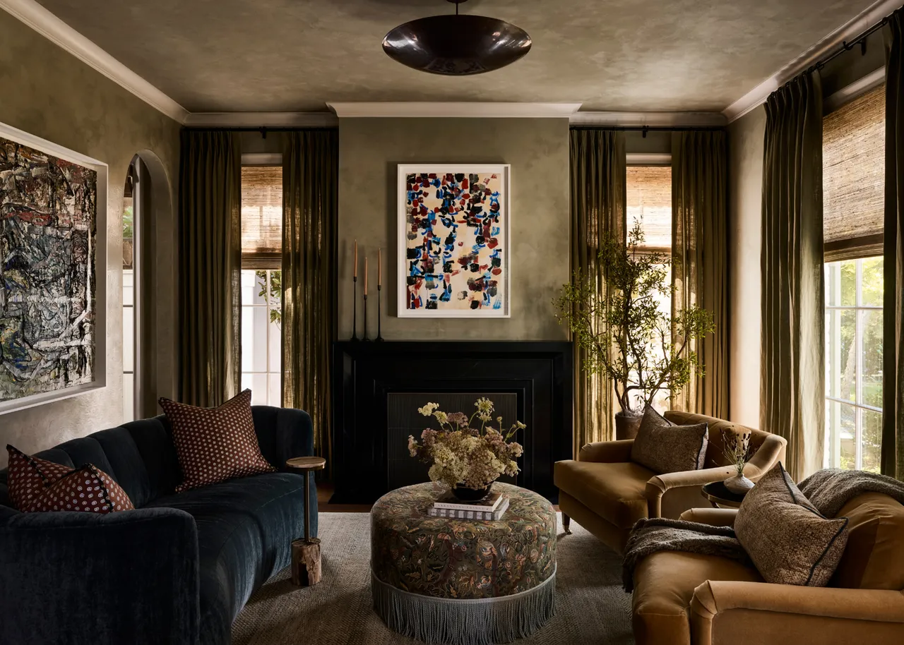 A dark blue sofa sits beside warm upholstered chairs in a richly colored room.