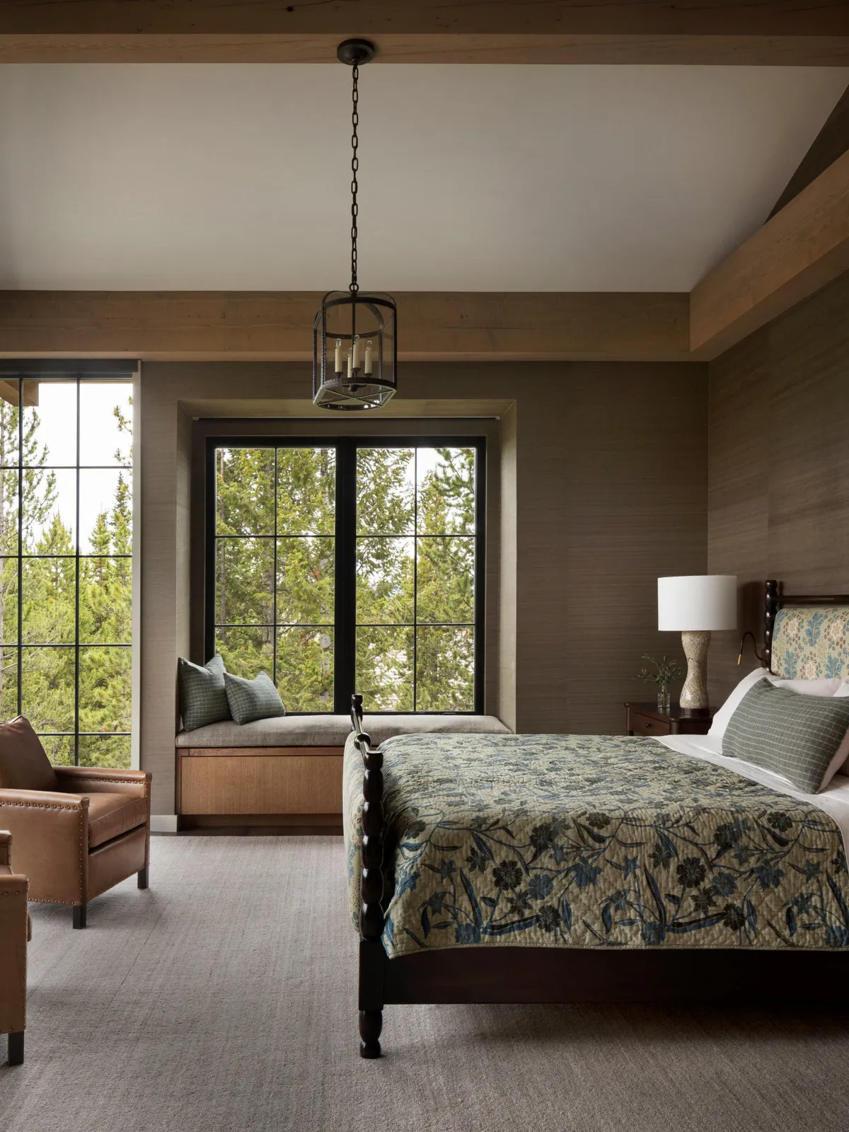 A timber bed and built-in window bench sit beneath exposed ceiling beams.