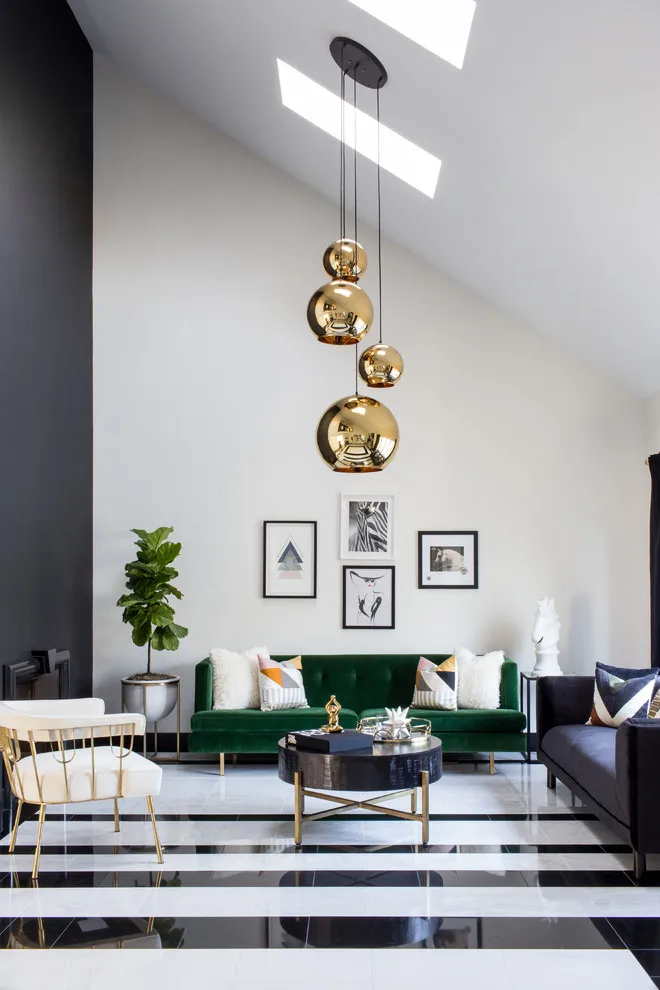 Small dark frames form a compact group above a green sofa in a tall room