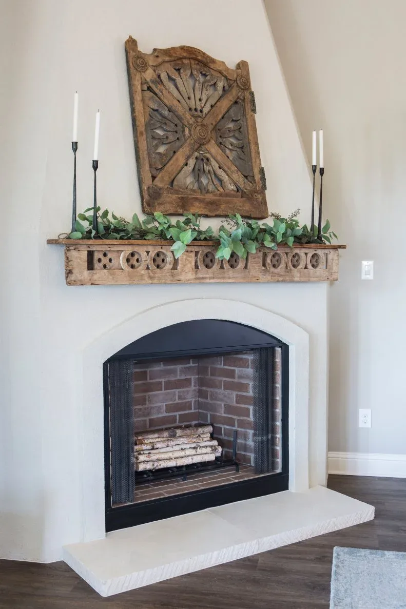 White angled fireplace with an arched dark opening, carved wood mantel and carved panel above.