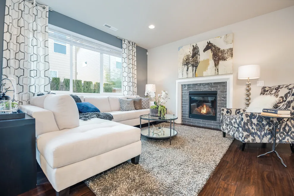 A patterned chair faces a white sectional near a tiled fireplace