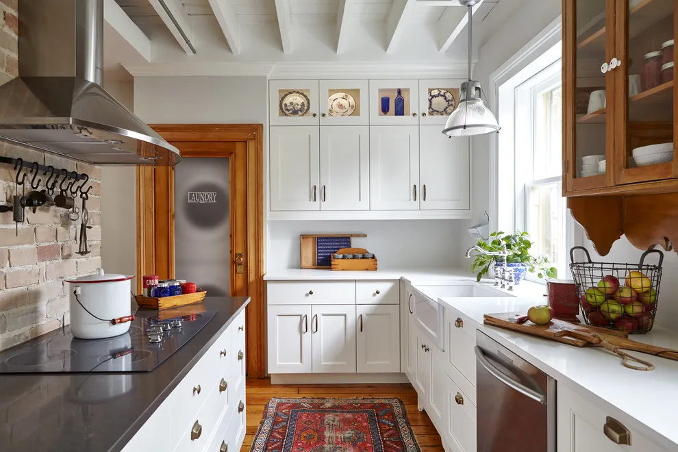 White cabinets sit beside warm timber trim and a dark worktop in a bright kitchen