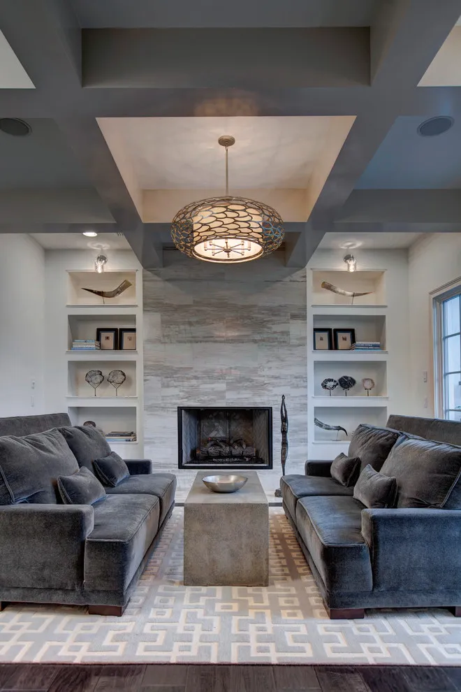 Dark gray sofas sit on either side of a long wooden table beneath a decorative ceiling light
