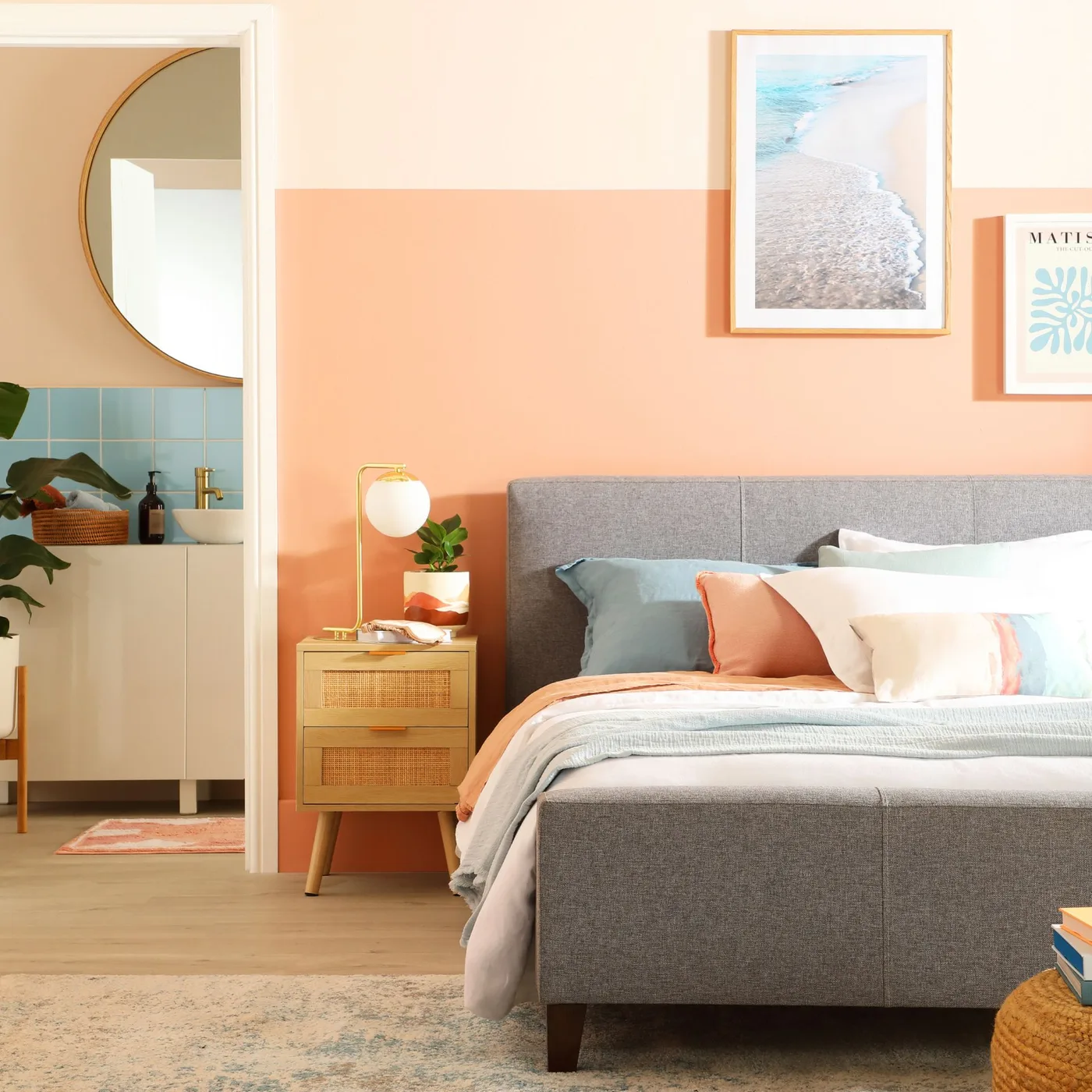 Bedroom with coral lower walls, a gray upholstered bed, pale blue bedding accents and a framed shoreline photograph.