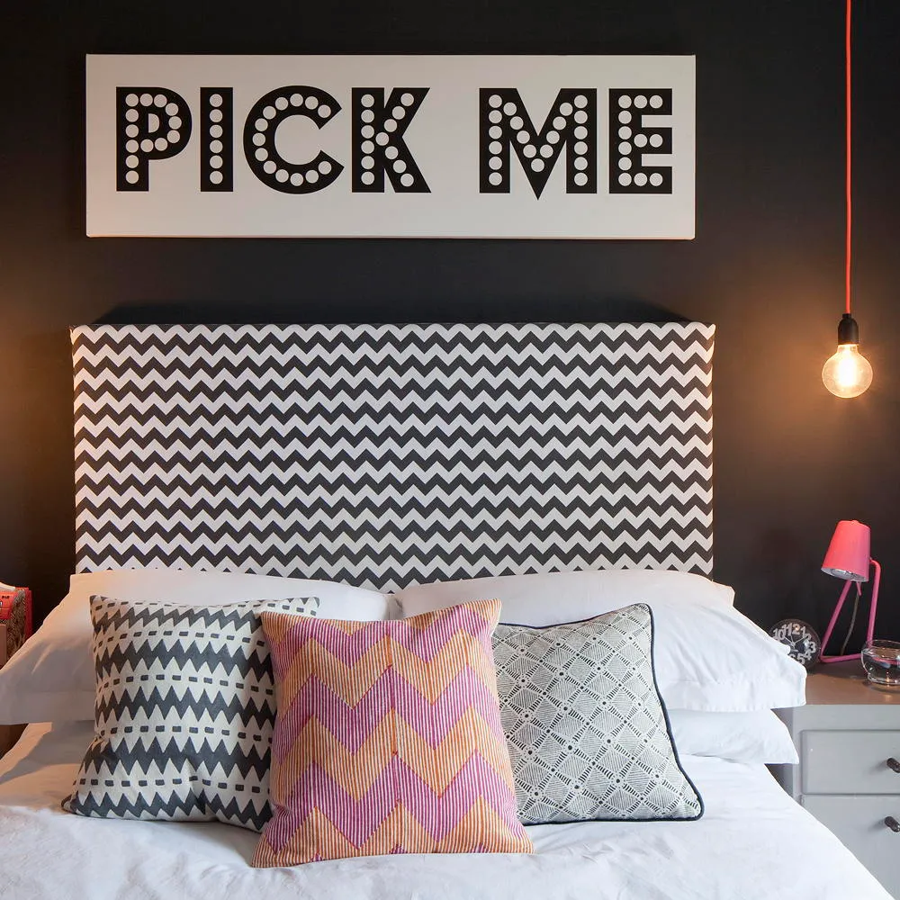 A black-and-white zigzag headboard sits against a dark wall above pale bedding