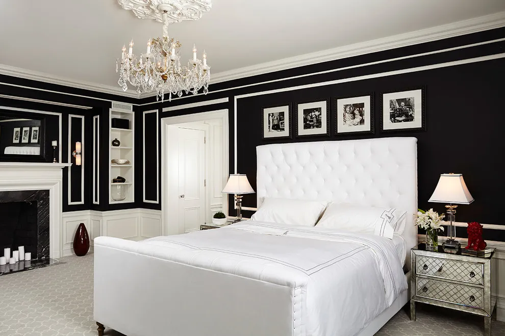 A white upholstered bed stands against black walls with white decorative trim