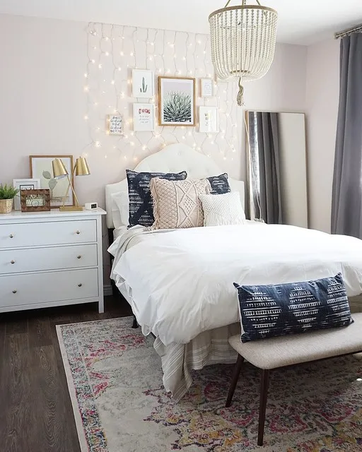A bright bedroom pairs white bedding with patterned blue pillows and a pale pendant.