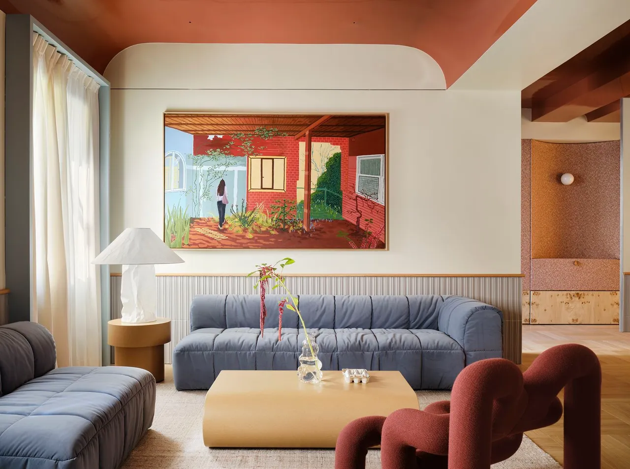 Pale blue seating sits beneath warm neutral walls and a rust-colored ceiling section.
