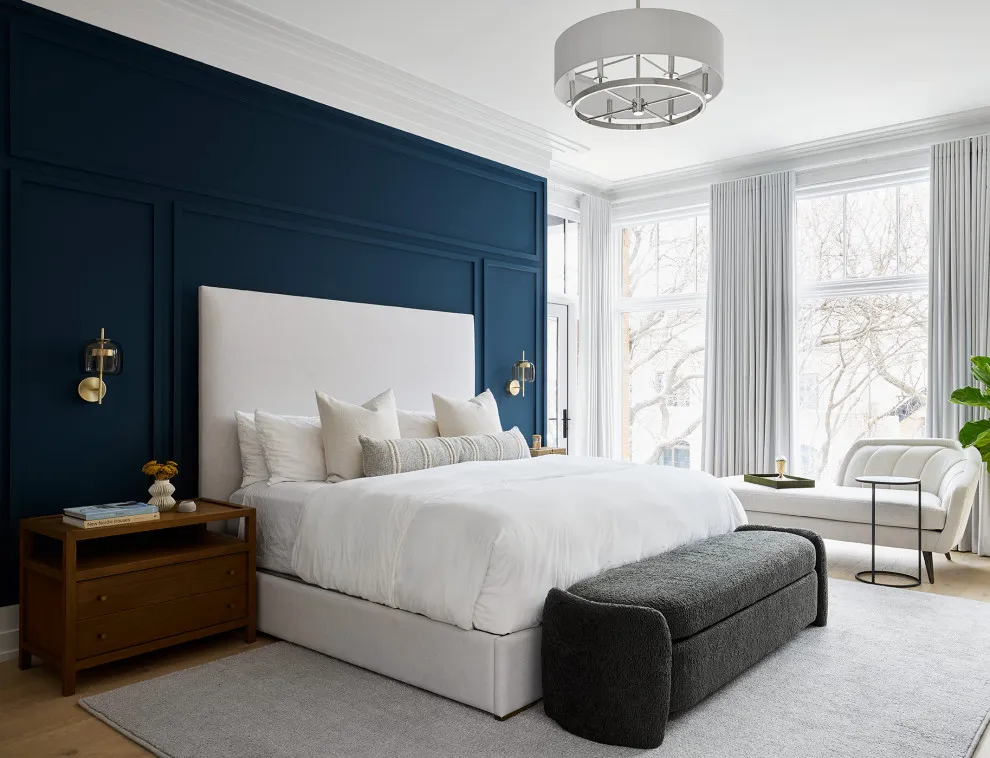 Navy panels sit behind a white upholstered bed and a dark bench