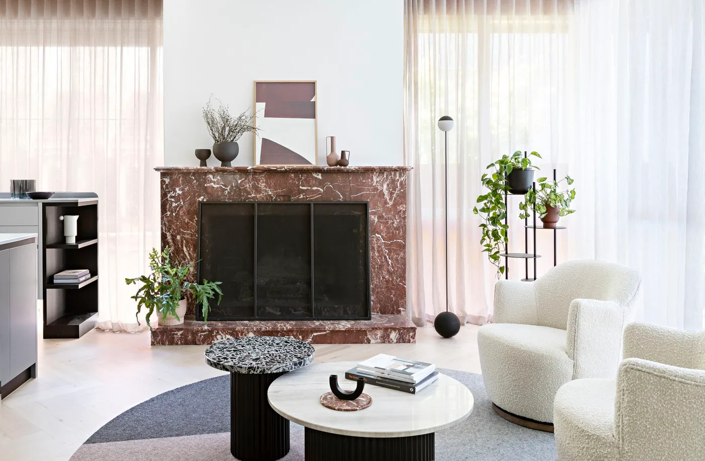 Burgundy and pale veined fireplace with geometric picture, small vessels, plants and white chairs