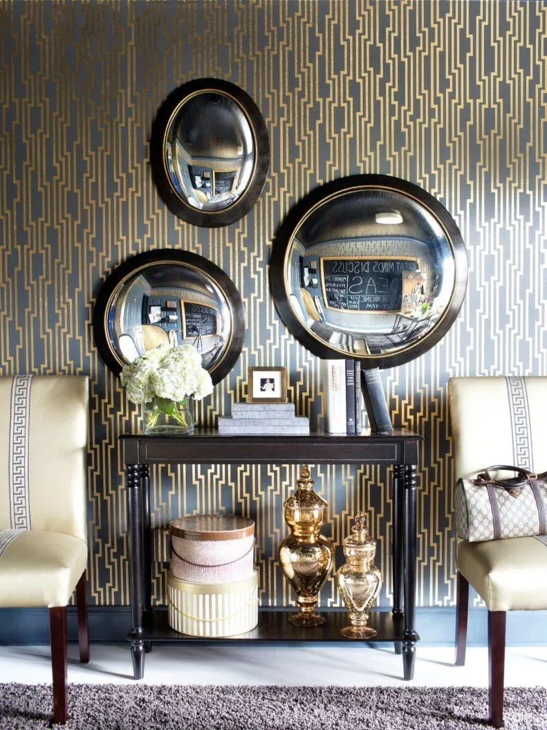 Three convex round mirrors above a narrow black shelf against gold-lined patterned office wallpaper.