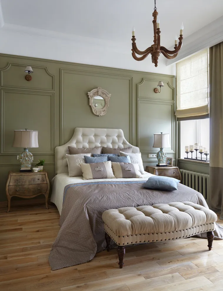 Green paneled walls surround a light bed and tufted bench