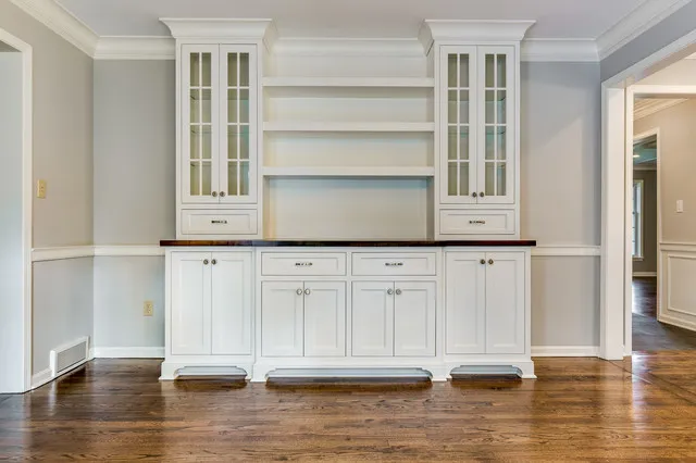 A pale built-in cupboard offers drawers, enclosed shelves and a central display section.